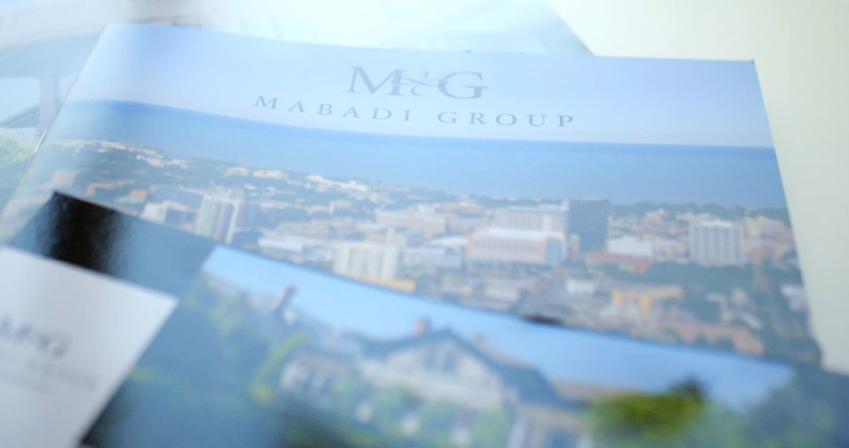 The Mabadi Group brochure with cover in background and interior spread in foreground