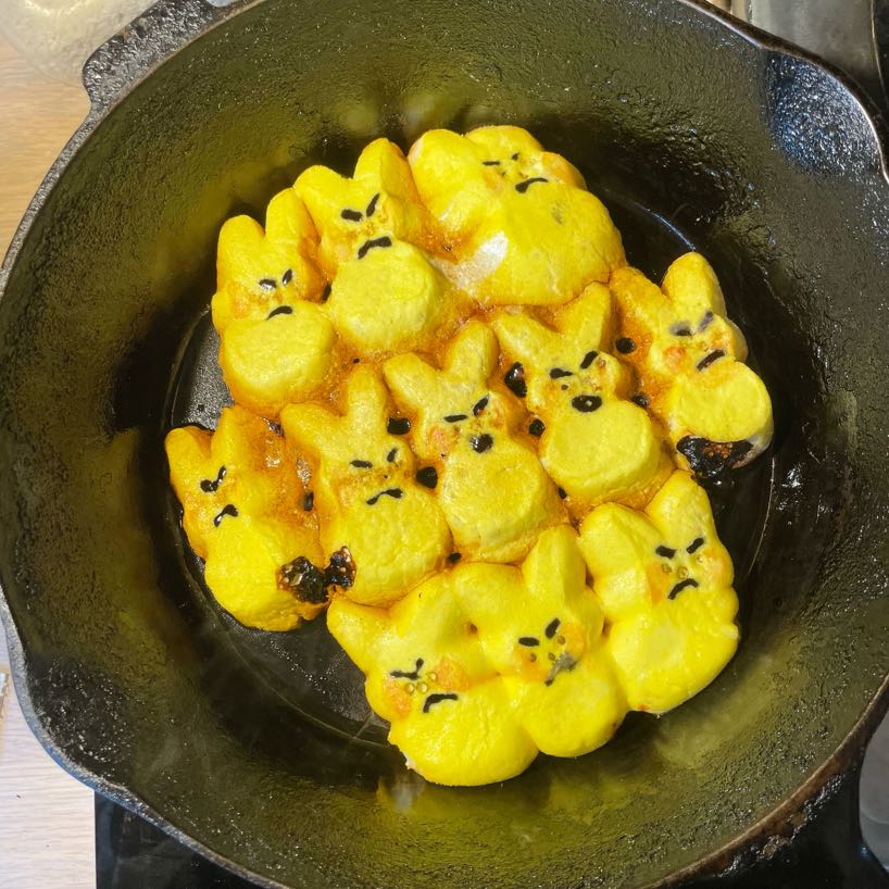 Yellow rabbit peeps with angry expressions frying in an iron skillet