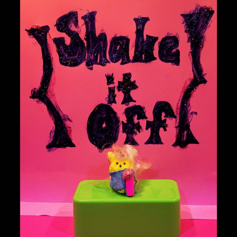 Yellow rabbit Peep dressed as Taylor Swift on a green stage in front of words Shake it Off